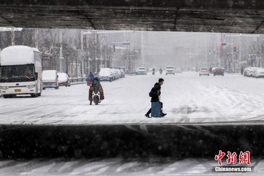 河南迎降雪天气 民众冒雪拎行李箱出行